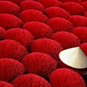 Bright red incense sticks drying in the sun with a conical hat adding cultural flair.